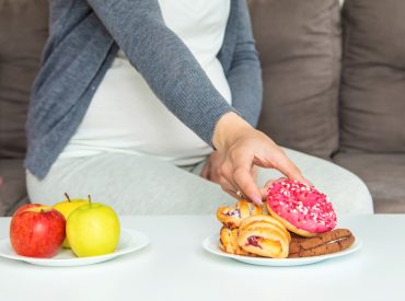 A pregnant woman eats a sweet donut. Selective focus. trastornos alimentarios qué son
