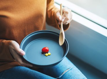 Closeup image of a woman holding a plate of small amount of food Closeup image of a woman holding a plate of small amount of food for diet concept